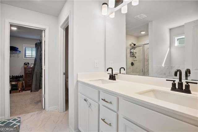 full bathroom featuring a sink, marble finish floor, a shower stall, and a walk in closet