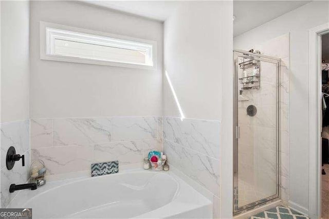 bathroom with a garden tub, a spacious closet, and a shower stall