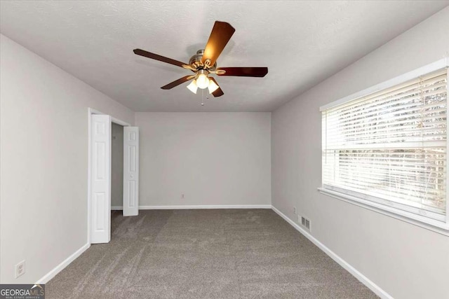 carpeted empty room with ceiling fan and a textured ceiling