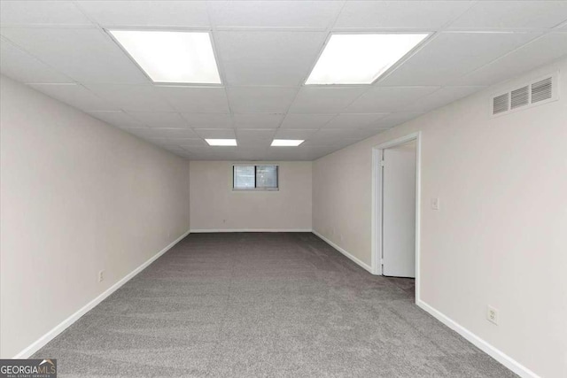 basement featuring a paneled ceiling and carpet