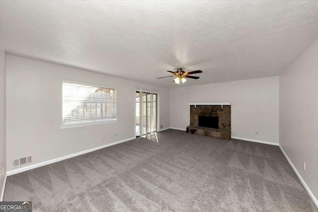 unfurnished living room featuring ceiling fan, carpet, a textured ceiling, and a fireplace