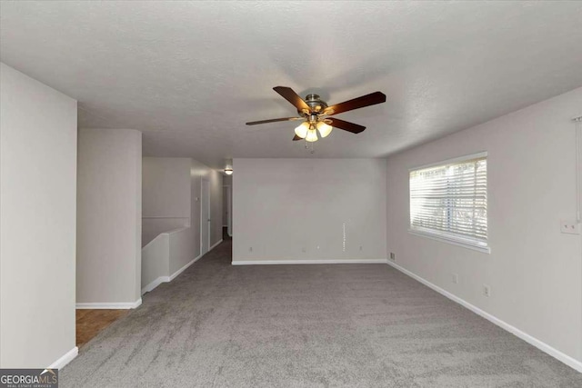 carpeted spare room featuring a textured ceiling and ceiling fan