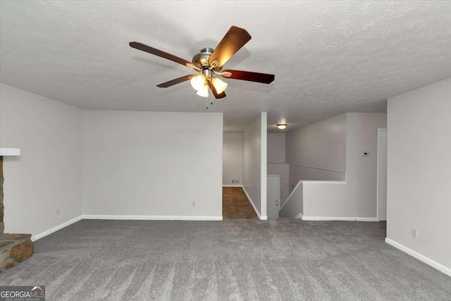 unfurnished living room with ceiling fan, a textured ceiling, and dark carpet