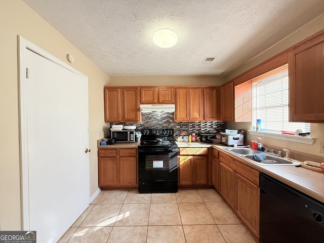 kitchen with sink, light tile patterned floors, black appliances, and a textured ceiling