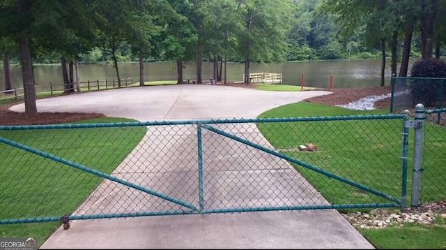 surrounding community with a yard, a water view, fence, and a gate