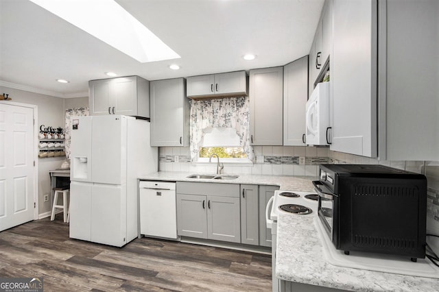 kitchen featuring white appliances, a skylight, sink, dark hardwood / wood-style floors, and gray cabinets