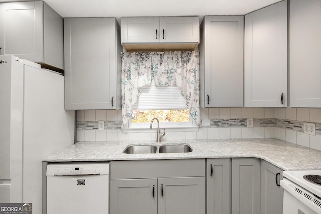 kitchen with sink, white dishwasher, gray cabinetry, and tasteful backsplash