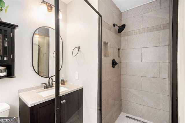 bathroom with vanity, toilet, and a tile shower