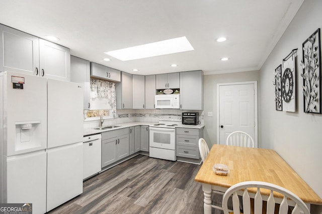 kitchen with white appliances, a skylight, sink, gray cabinets, and ornamental molding