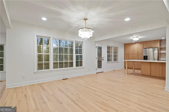 unfurnished living room featuring light wood-type flooring and a notable chandelier