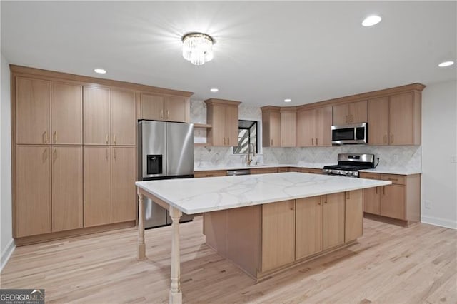 kitchen with light hardwood / wood-style floors, light stone counters, a center island, and stainless steel appliances