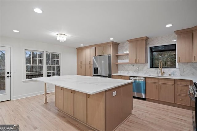 kitchen featuring appliances with stainless steel finishes, a kitchen island, tasteful backsplash, light hardwood / wood-style floors, and sink