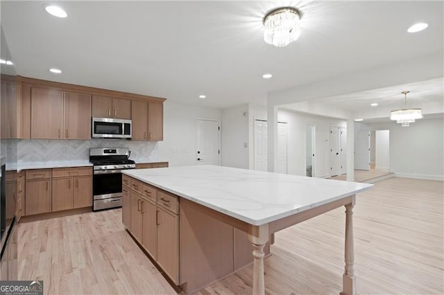 kitchen featuring decorative light fixtures, stainless steel appliances, a notable chandelier, and a kitchen island