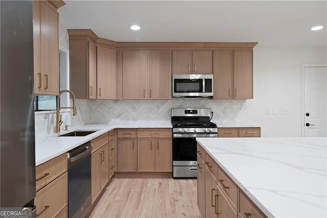 kitchen with sink, stainless steel appliances, light stone counters, and backsplash