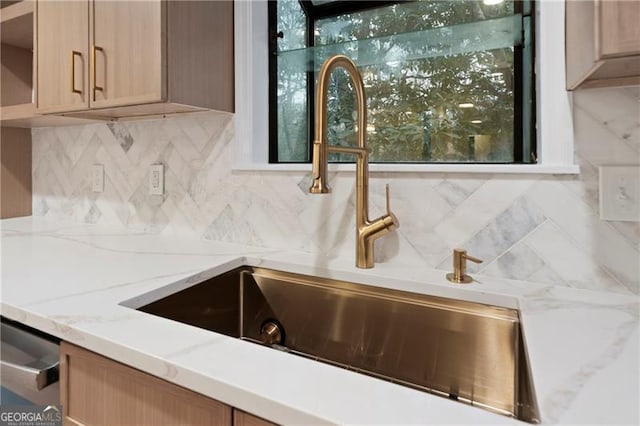 kitchen with light stone countertops, tasteful backsplash, dishwasher, sink, and light brown cabinets