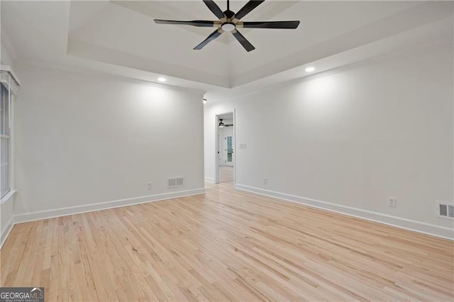 unfurnished room featuring ceiling fan, light hardwood / wood-style floors, and a raised ceiling