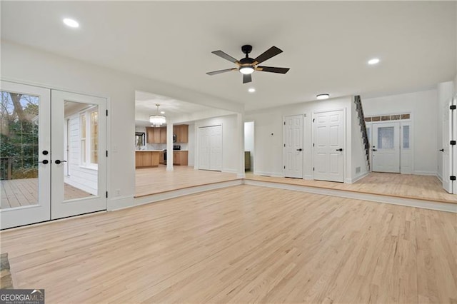 unfurnished living room with light hardwood / wood-style flooring, ceiling fan, and french doors