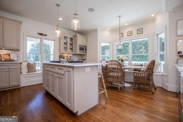 kitchen featuring decorative light fixtures, a kitchen bar, stainless steel microwave, and a kitchen island