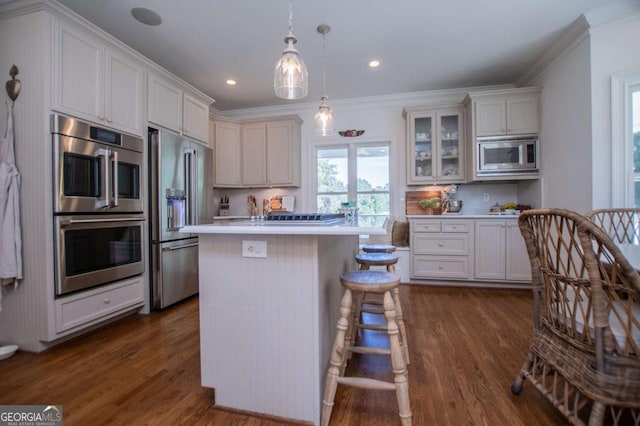 kitchen featuring decorative light fixtures, dark wood-type flooring, a kitchen island, decorative backsplash, and stainless steel appliances