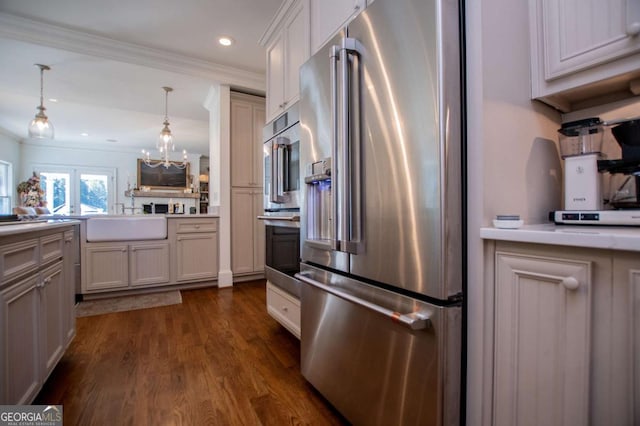 kitchen featuring high end fridge, sink, decorative light fixtures, kitchen peninsula, and dark wood-type flooring