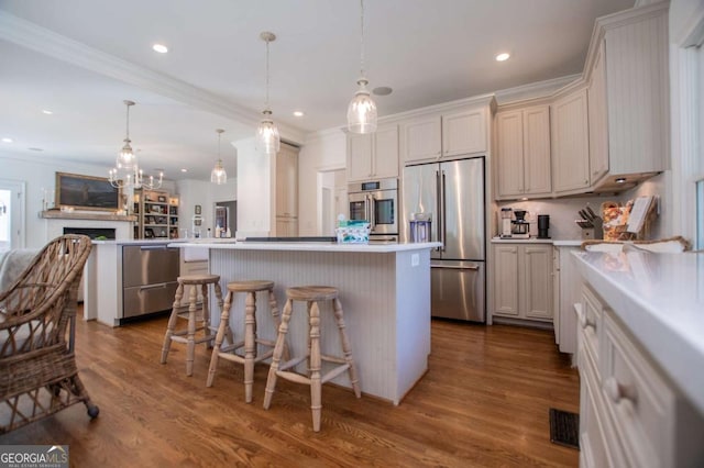 kitchen featuring a kitchen breakfast bar, dark hardwood / wood-style flooring, decorative light fixtures, appliances with stainless steel finishes, and a center island