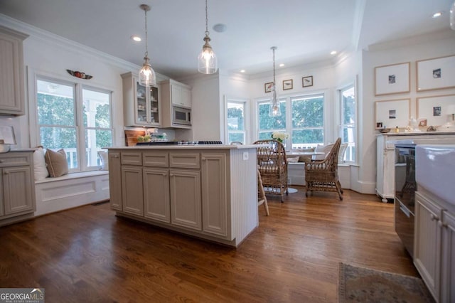 kitchen with a center island, stainless steel microwave, ornamental molding, pendant lighting, and dark hardwood / wood-style flooring