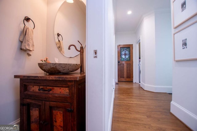 hall featuring sink, ornamental molding, and light wood-type flooring