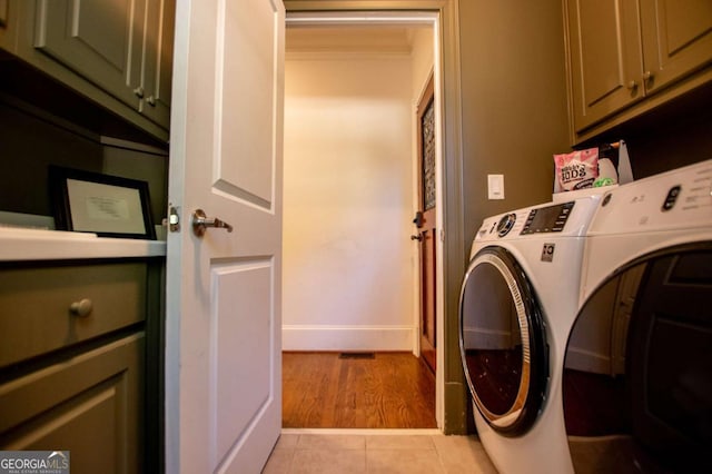 washroom featuring light tile patterned floors, cabinets, and washer and dryer