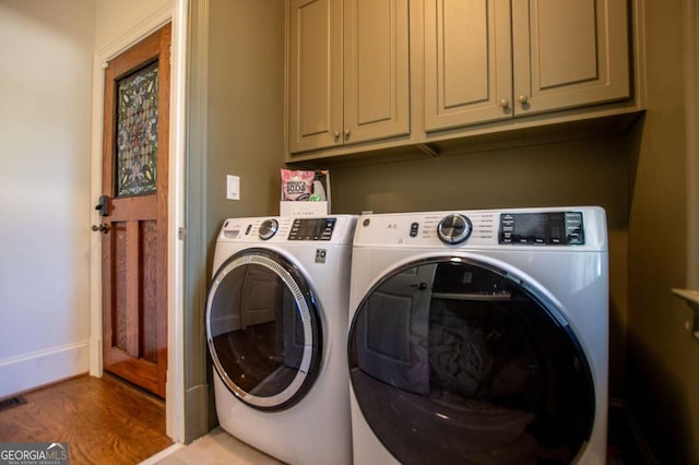 clothes washing area featuring washer and dryer, cabinets, and light hardwood / wood-style floors