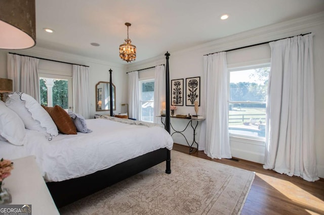 bedroom featuring a notable chandelier, hardwood / wood-style floors, multiple windows, and crown molding