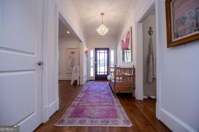 foyer with crown molding, an inviting chandelier, and dark hardwood / wood-style floors