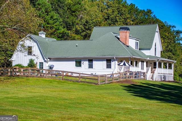 back of property with covered porch and a yard