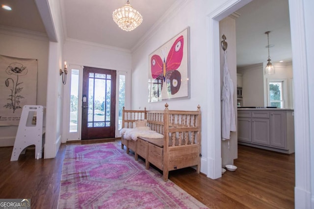 foyer with dark hardwood / wood-style flooring, ornamental molding, and a notable chandelier