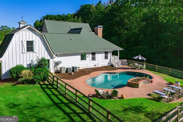 rear view of property with a fenced in pool, a yard, a patio, and central AC