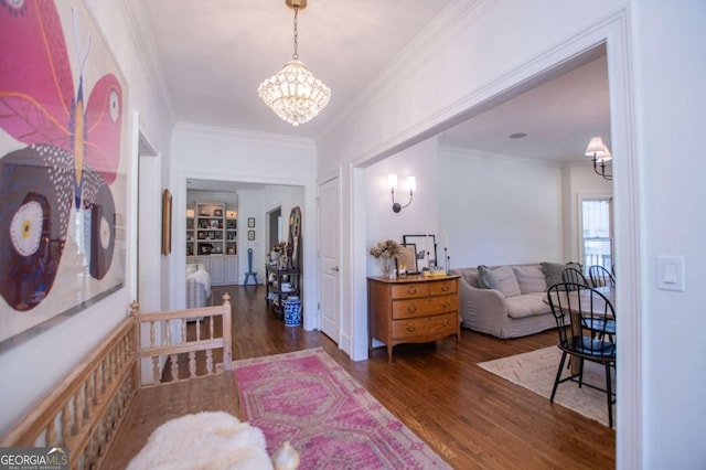 entrance foyer with a chandelier, ornamental molding, and dark hardwood / wood-style flooring