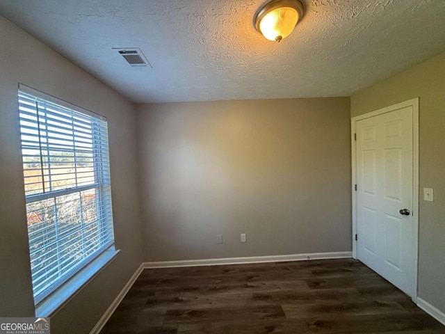 spare room with dark wood-type flooring and a textured ceiling