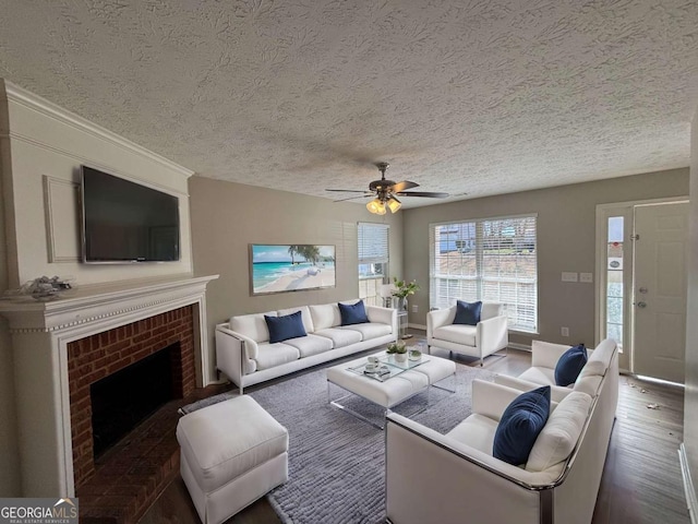 living room featuring ceiling fan, a textured ceiling, dark hardwood / wood-style flooring, and a fireplace