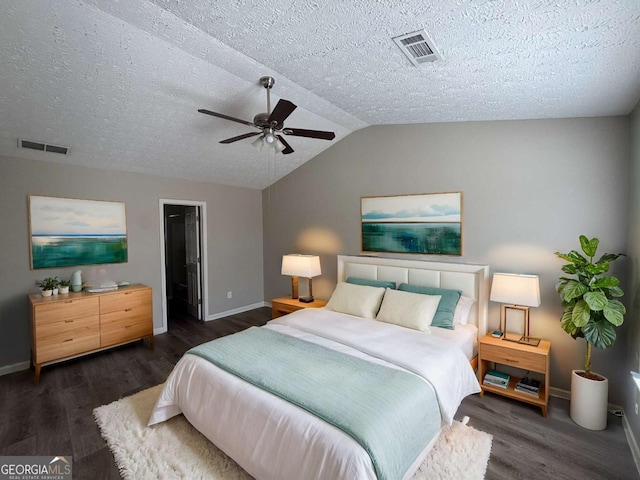 bedroom featuring a spacious closet, a textured ceiling, dark hardwood / wood-style flooring, vaulted ceiling, and ceiling fan