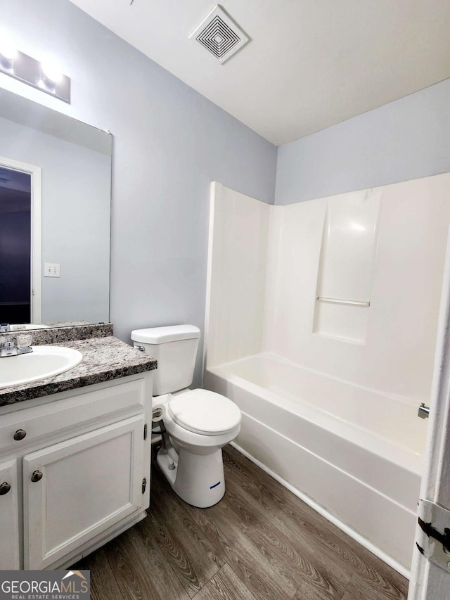 full bathroom with vanity, hardwood / wood-style flooring, shower / tub combination, and toilet