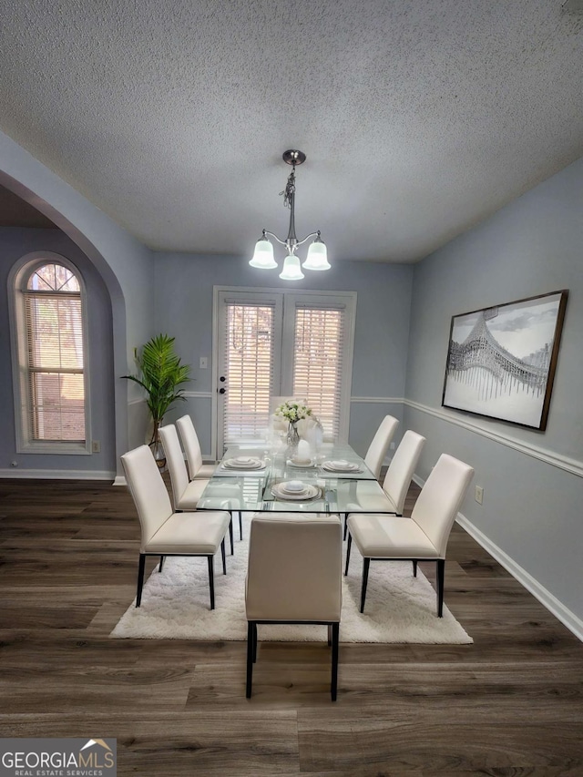 dining room featuring a notable chandelier, dark hardwood / wood-style floors, and a textured ceiling