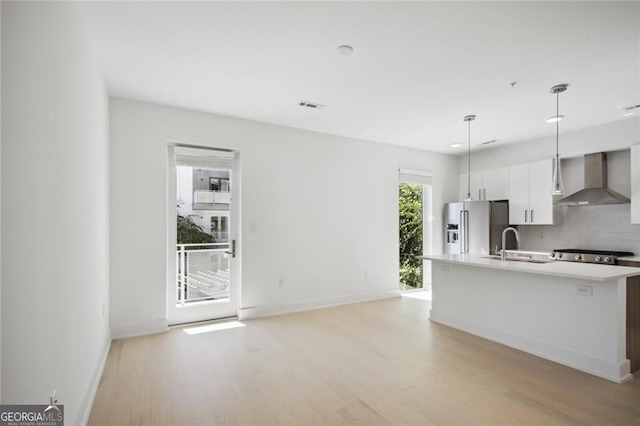 kitchen featuring wall chimney range hood, sink, backsplash, decorative light fixtures, and high end refrigerator