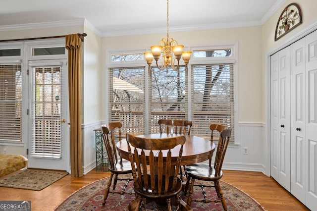 dining space featuring light hardwood / wood-style floors, crown molding, and a notable chandelier