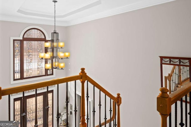 staircase featuring a chandelier, crown molding, and a tray ceiling