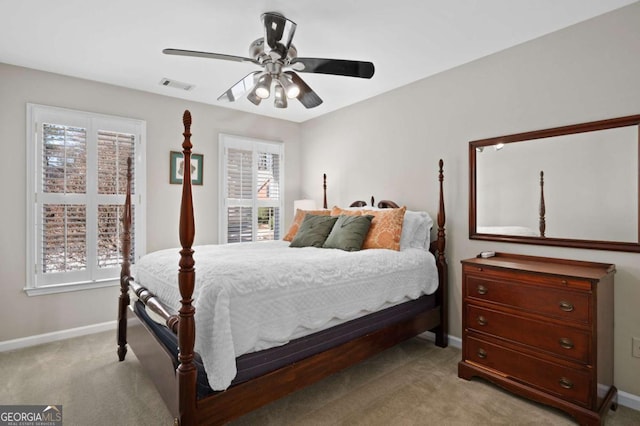 bedroom with ceiling fan, light colored carpet, and multiple windows