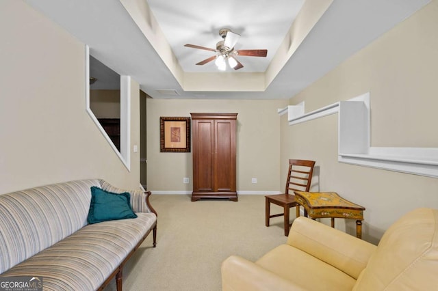 carpeted living room featuring ceiling fan and a tray ceiling