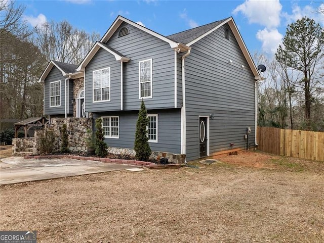 view of side of home with a gazebo, a patio, driveway, and fence