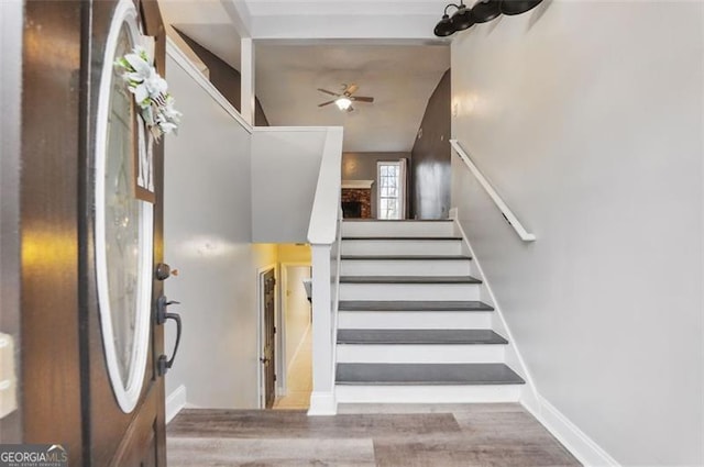 stairway featuring baseboards, a ceiling fan, and wood finished floors