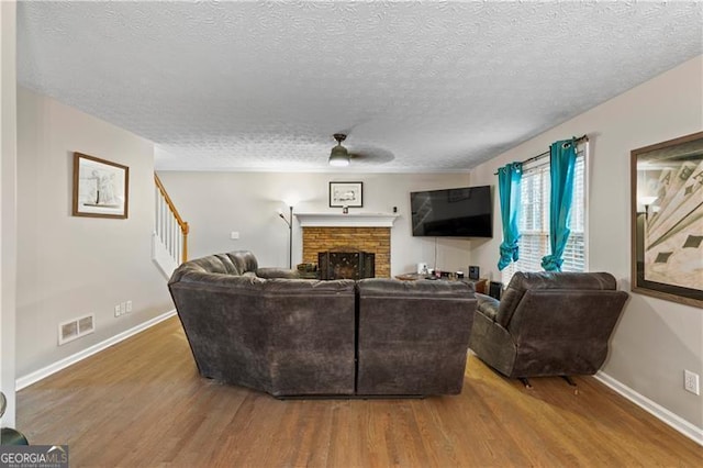 living room with a textured ceiling, wood-type flooring, and ceiling fan