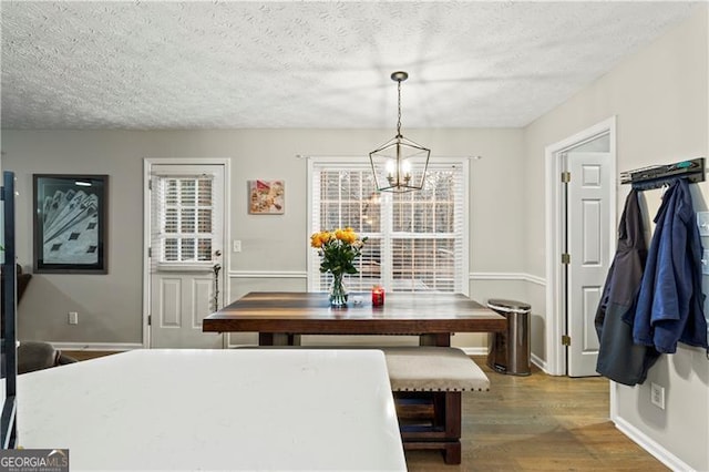 dining area with an inviting chandelier, dark hardwood / wood-style floors, and a textured ceiling