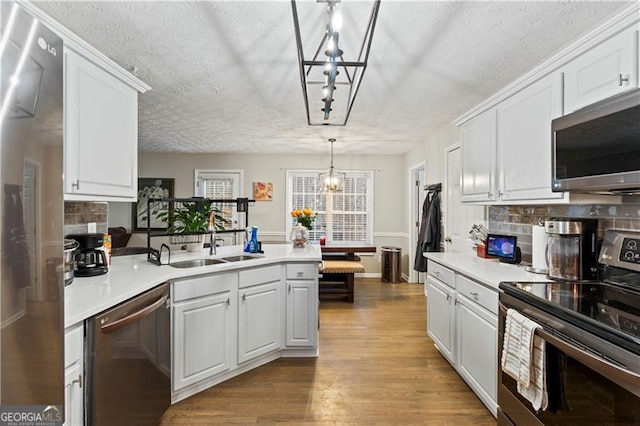 kitchen featuring white cabinetry, hanging light fixtures, hardwood / wood-style floors, stainless steel appliances, and a notable chandelier